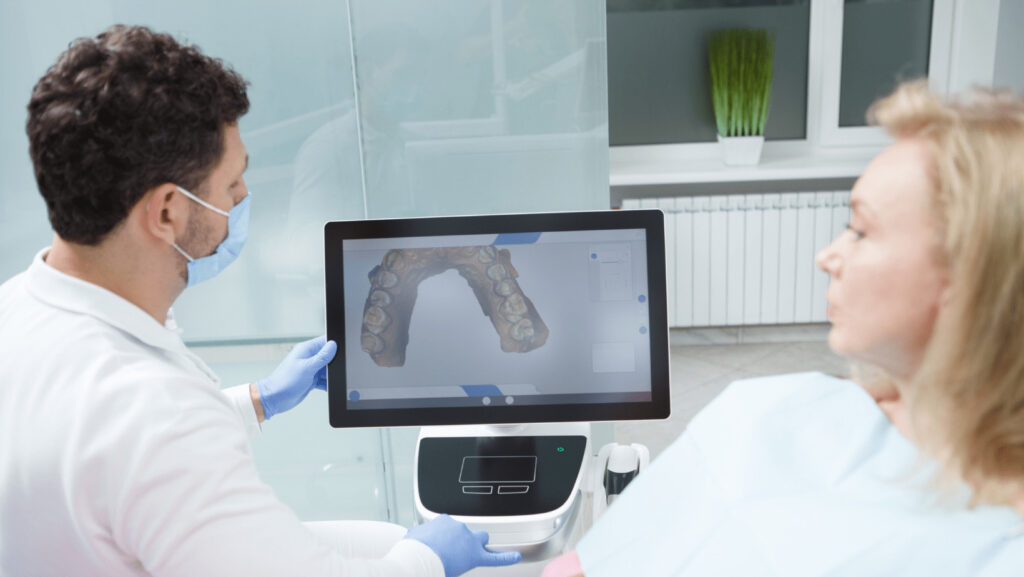 A man and woman in white lab coats are discussing a dental treatment plan.