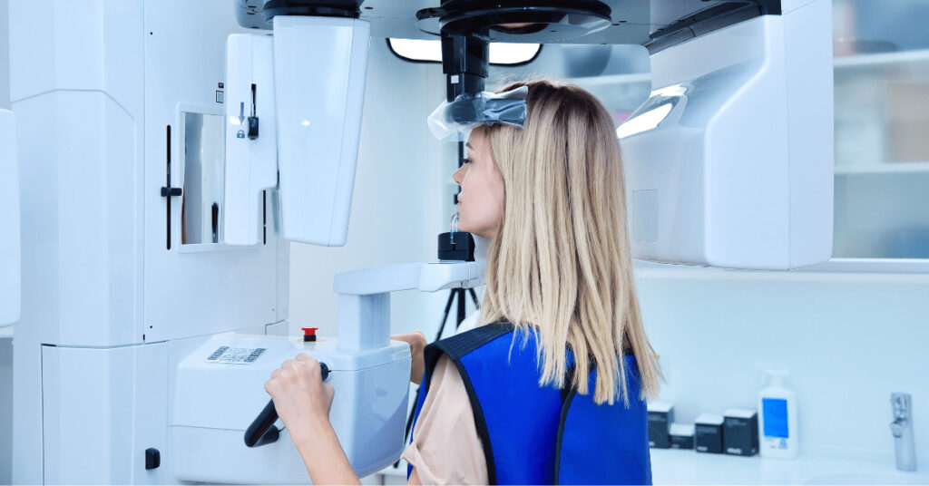 A woman in a lab conducting dental research while looking into a microscope.